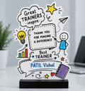 A custom cartoon-style acrylic award plaque on a black base, featuring hand-drawn illustrations and text celebrating a trainer named Patil Vishal, displayed on a light marble surface with a blurred office background.